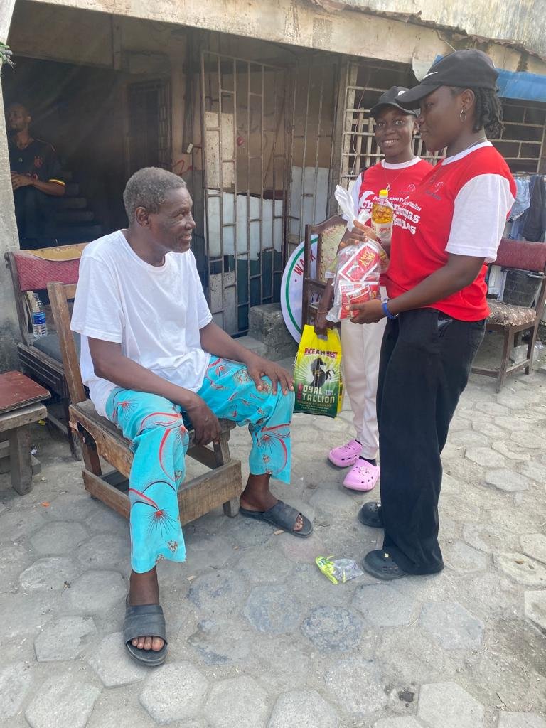 Foundation volunteers presenting food items to a seated community member