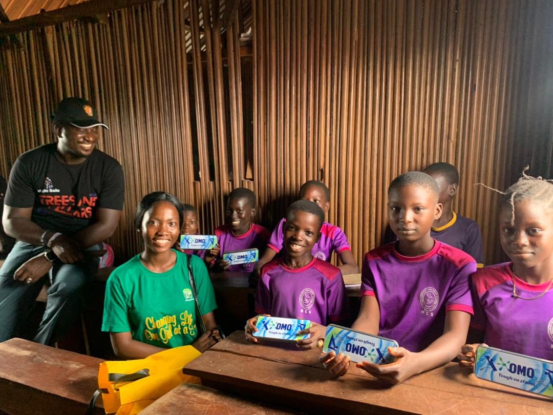 Children receiving classroom and hygiene materials inside a wooden school space